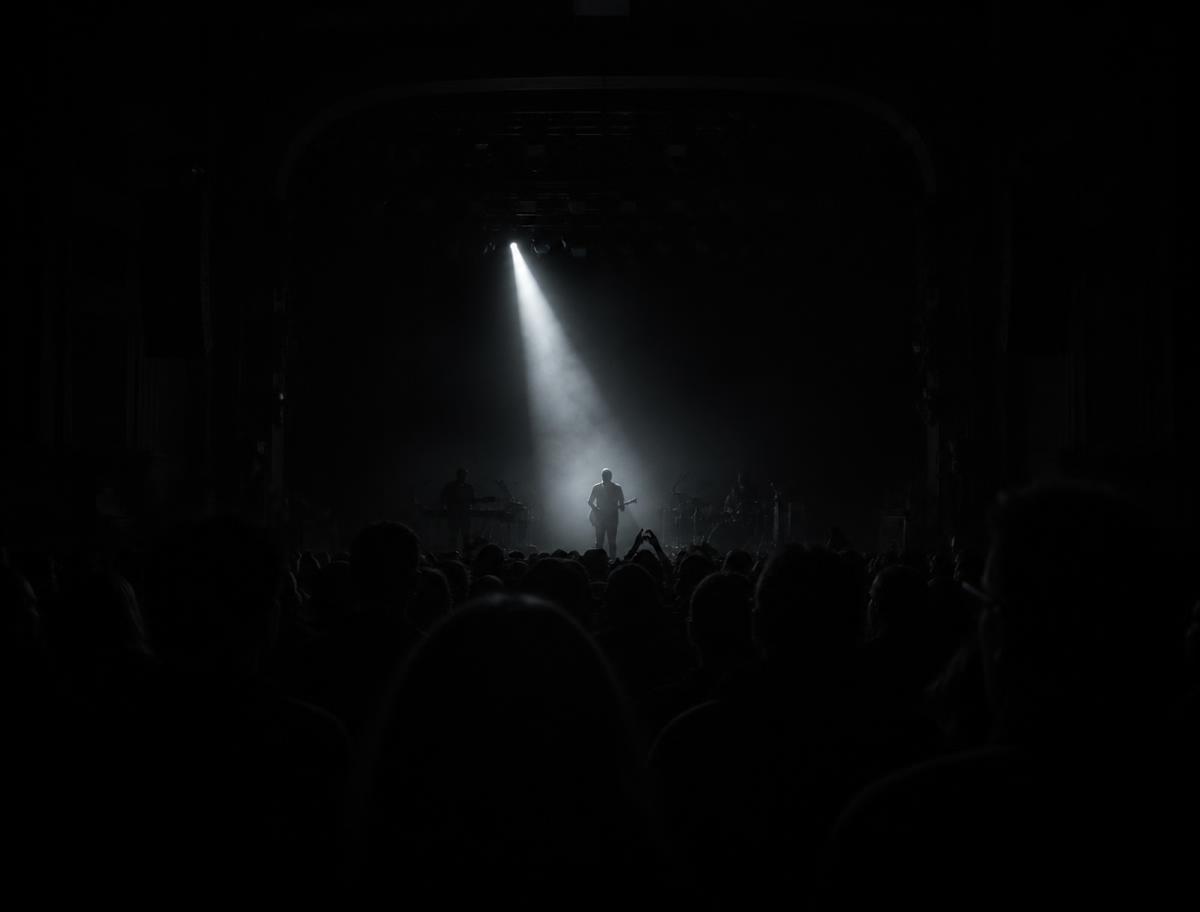 Show ao vivo visto do fundo da plateia com um feixe de luz sobre o palco